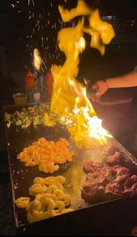 Hibachi chef performing live fire cooking in backyard